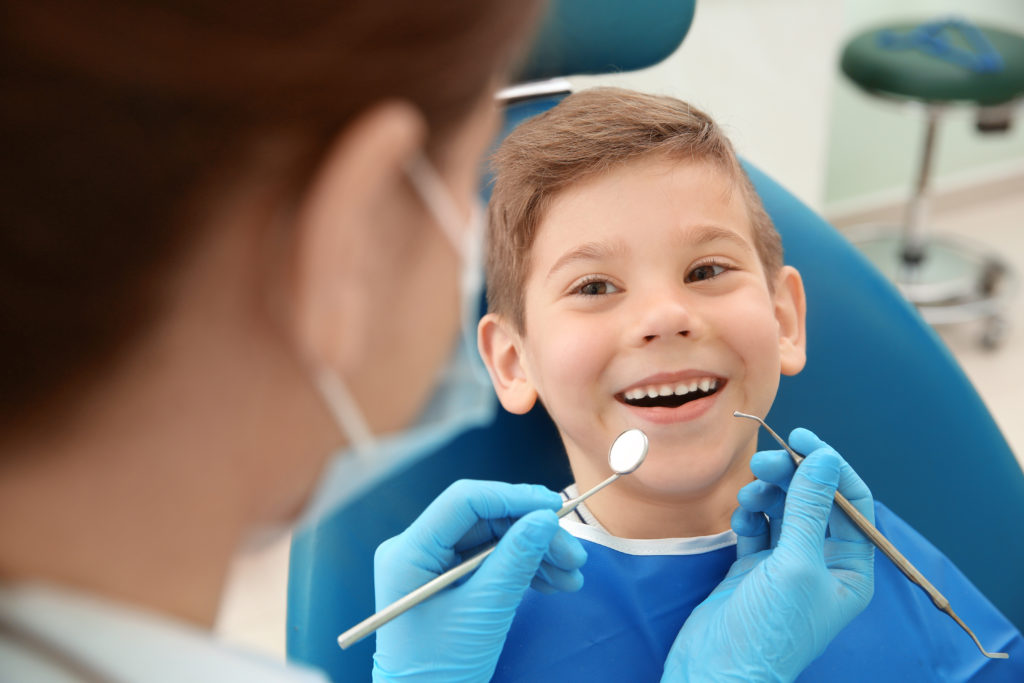 Pediatric Dentist examining little boy's teeth in clinic
